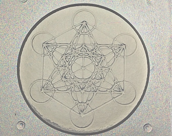 May include: A gray, circular, ceramic mold with a raised design of a geometric pattern. The pattern is a complex, interwoven design of triangles, circles, and lines.