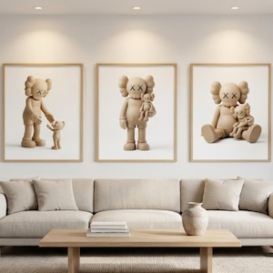 Peut inclure: Trois cadres muraux représentant des figurines KAWS couleur beige dans différentes positions. L'impression de gauche montre une figurine debout tendant la main vers une plus petite. Le centre montre une figurine en tenant une autre. À droite, deux figurines assises.