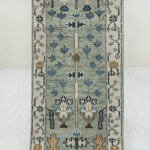 May include: A rectangular, patterned rug with a light green background. The rug features a repeating floral design in blue, yellow, and white. The rug is approximately 152 cm long.