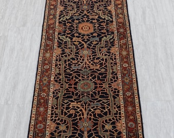 May include: A long, rectangular rug with an intricate, symmetrical pattern. The rug features a dark navy blue field with a repeating floral and geometric design in shades of rust, beige, and teal. The border is a rust color with a repeating floral pattern.