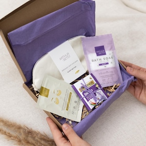 May include: A gift box containing sleep-related products. The box is brown with purple tissue paper and contains a white eye mask, bath soak, eye mask sachets, and tea. The products are branded with the name "Arthur Betsy".