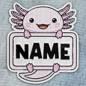 May include: Embroidered patch featuring a smiling axolotl holding a sign that reads "NAME" in black letters. The axolotl is pink with black eyes and pink gills. The patch has a white border and is set against a blue denim background.
