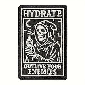 May include: Black and white embroidered patch featuring a grim reaper holding a water bottle. The patch has the words "HYDRATE" at the top and "OUTLIVE YOUR ENEMIES" at the bottom. The reaper is in a hooded cloak.