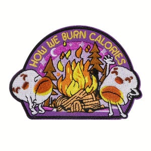 May include: Embroidered patch with a purple border and the text "HOW WE BURN CALORIES". The patch features a campfire with two cartoon marshmallows. The marshmallows have orange and brown accents and are dancing near the fire.
