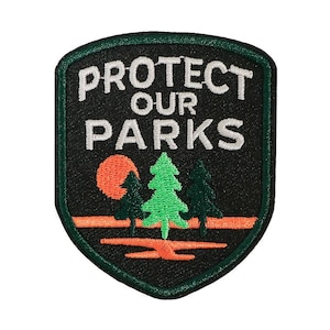 May include: Embroidered patch with the words "PROTECT OUR PARKS" in white. The patch features a black background with a green border, an orange sun, and green and dark green trees.
