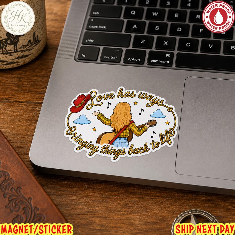 May include: An oval sticker featuring a person with long blonde hair playing an acoustic guitar. The text reads Love has ways, Bringing things back to life. A red cowboy hat, blue clouds, and musical notes surround the figure, all framed by a rope border.