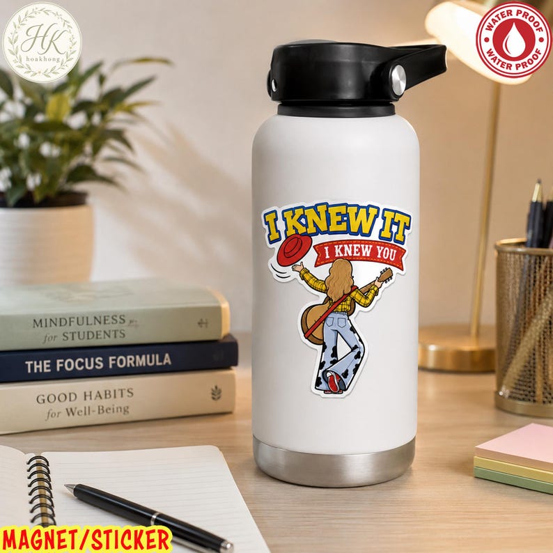 May include: A white water bottle with a black lid featuring a sticker of a person with long hair wearing a yellow plaid shirt and cow-print bell-bottoms, holding a guitar and a red hat, with the text I KNEW IT I KNEW YOU printed above.