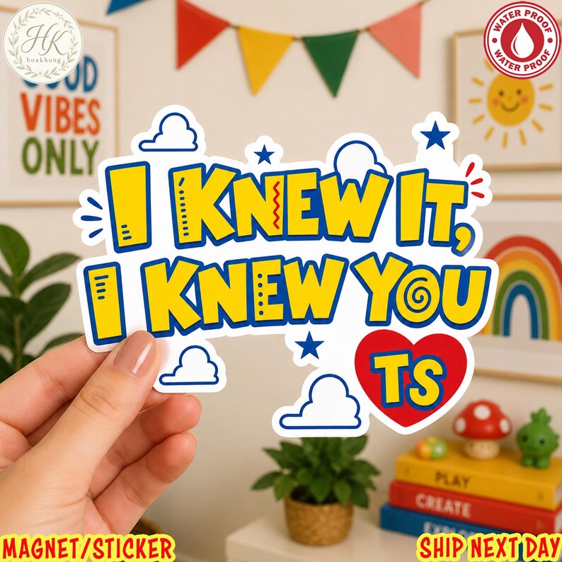 May include: A die-cut sticker featuring the yellow text I KNEW IT, I KNEW YOU TS with a blue outline. The design includes small blue stars, white cloud outlines, and a red heart shape containing the letters TS, all on a white background.