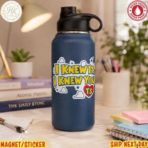 May include: A matte navy blue water bottle with a black screw-top lid and a carry loop. A white sticker on the front features the yellow text I KNEW IT, I KNEW YOU TS with a red heart and blue cloud graphics. The bottle has a waterproof design.