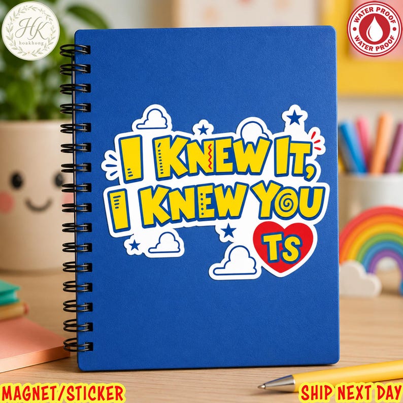 May include: A blue spiral-bound notebook featuring a central sticker with the yellow text I KNEW IT, I KNEW YOU, a red heart with the letters TS, and white cloud and blue star graphics. The sticker has a white border and a waterproof label.