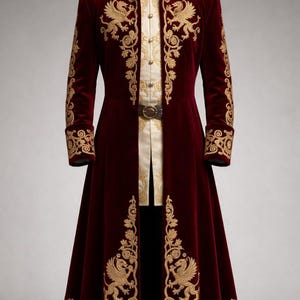 May include: A burgundy velvet coat with gold embroidery. The coat features ornate gold designs on the sleeves, front, and hem. It has a high collar and is paired with a cream-colored shirt and a decorative belt. The coat is floor-length.