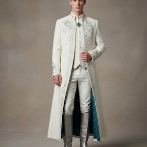 May include: A cream-colored, long coat with intricate silver embroidery and a matching vest and trousers. The coat features a high collar and a teal lining. The outfit is completed with silver knee-high boots and a teal and silver brooch.