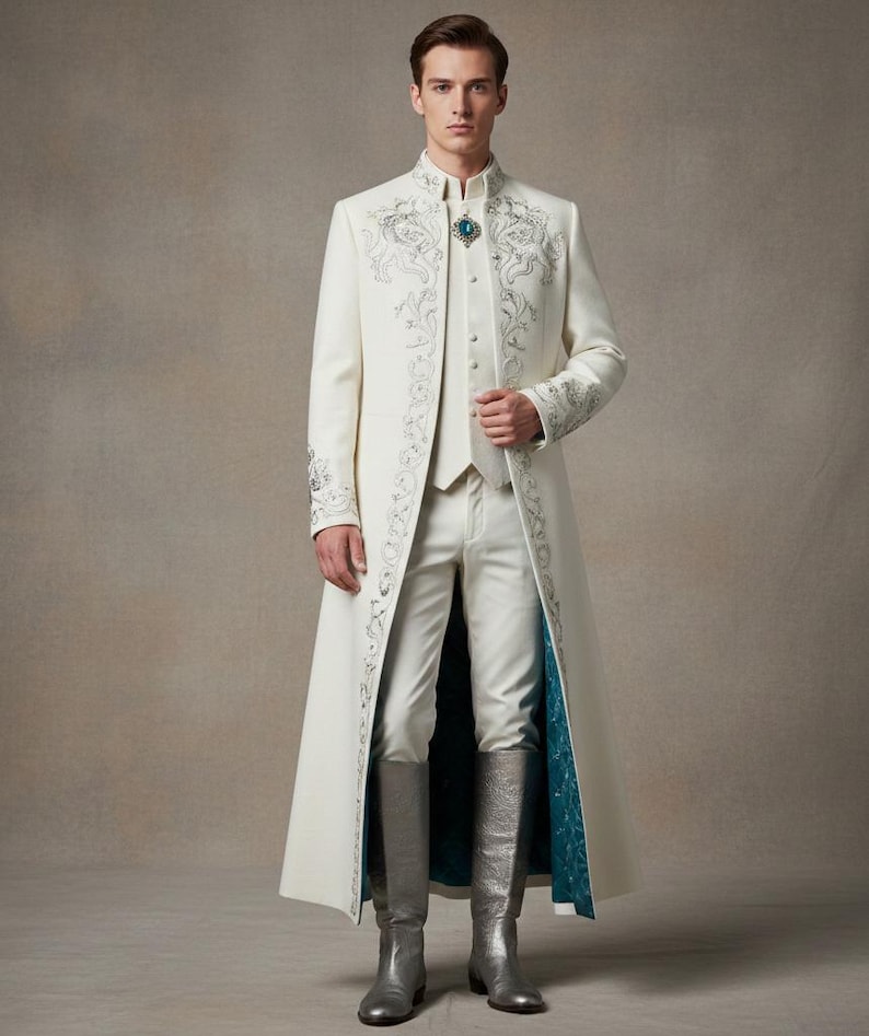 May include: A cream-colored, long coat with intricate silver embroidery and a matching vest and trousers. The coat features a high collar and a teal lining. The outfit is completed with silver knee-high boots and a teal and silver brooch.