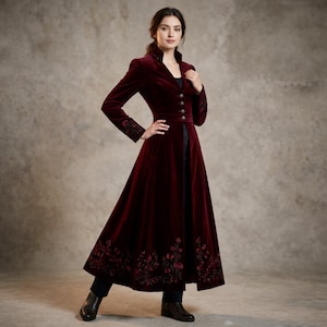 May include: A long, burgundy velvet coat with a high collar and button closure. The coat features floral embroidery on the sleeves and hem. The coat is floor-length and has a fitted waist.
