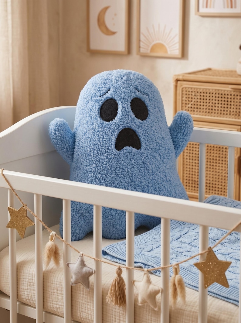 Pode incluir: Um brinquedo de pel&uacute;cia em forma de fantasma azul-claro com uma superf&iacute;cie texturizada semelhante a l&atilde; encaracolada. A pel&uacute;cia apresenta dois grandes olhos pretos ovais e uma boca preta oval menor, todos costurados na parte frontal do objeto.