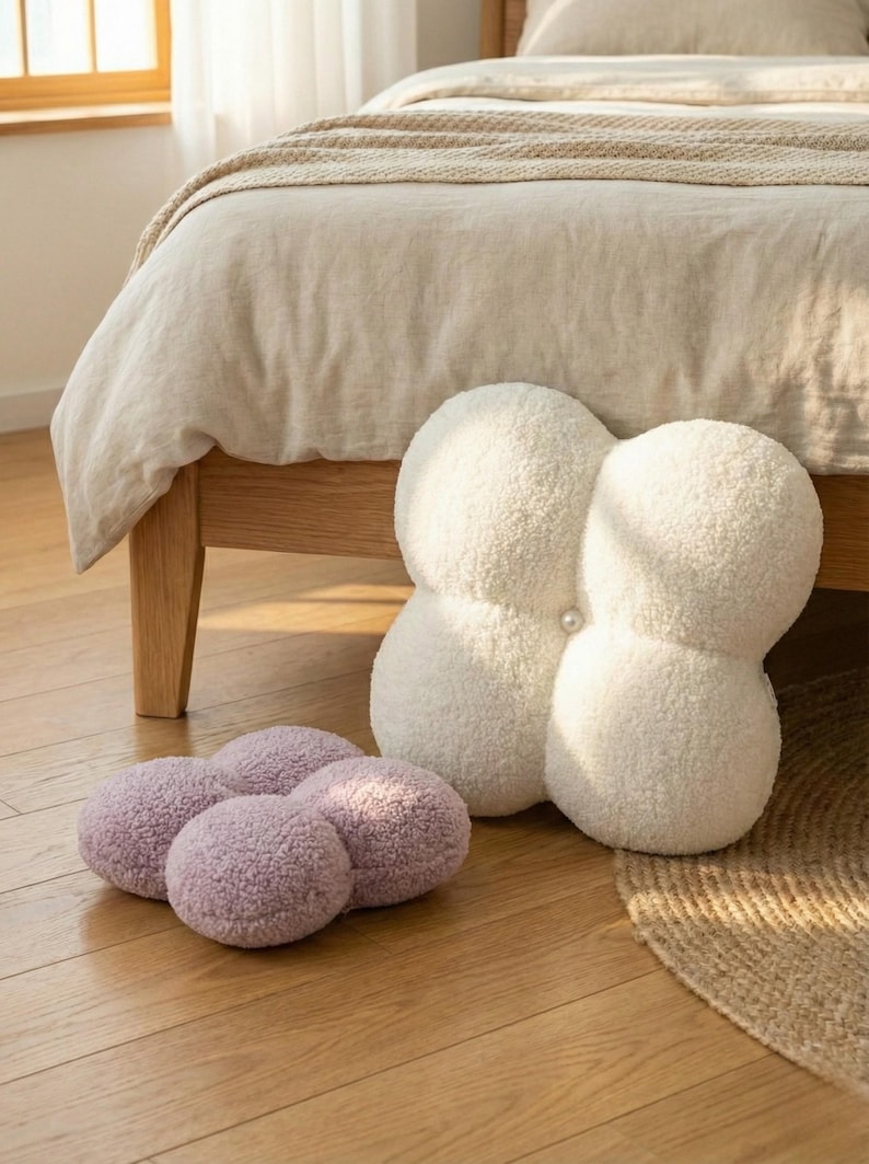 May include: A white ceramic mug with a black handle and the text "But First, Coffee" in a bold, black font. The mug is set against a blurred background, suggesting a cosy setting.