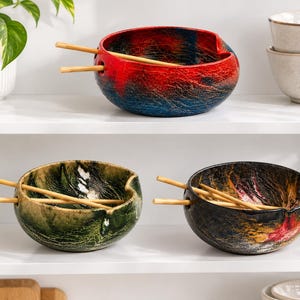 Può includere: Tre ciotole per ramen in ceramica con finiture smaltate testurizzate e multicolori, dotate di tacche laterali integrate per riporre le bacchette in legno. Una ciotola presenta un gradiente rosso e blu, un'altra è verde e nera, la terza è nera, rossa e oro.