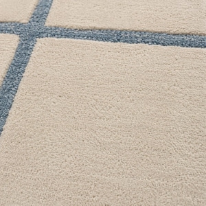 Modern beige and blue geometric rug with irregular windowpane design in closeup shot