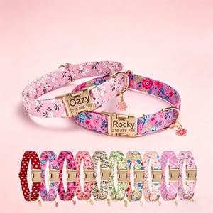 May include: A selection of dog collars with floral patterns in pink and other colours. The collars have gold-coloured buckles and name tags with the names "Ozzy" and "Rocky" and a phone number. Each collar has a small flower charm. The collars are in various floral designs.