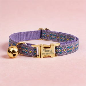 May include: A lavender pet collar featuring a woven geometric pattern in teal, yellow, and white. The collar includes a gold-toned metal buckle engraved with the name Elena and the number 218555789, along with a matching gold-toned jingle bell.