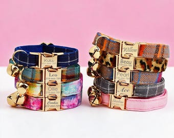 May include: Two stacks of pet collars featuring gold-tone metal buckles engraved with names and phone numbers. The collars display various patterns including plaid, leopard print, and solid colors, each equipped with a small gold-tone bell.