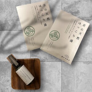 Könnte beinhalten: Draufsicht auf zwei beige Päckchen mit japanischem Text und einem grünen, kreisförmigen Emblem. Eine kleine, dunkle Flasche ätherischen Öls "KUROMOJI" liegt auf einem quadratischen Holzstück. Die Produkte sind auf einer grauen Fliesenoberfläche angeordnet.