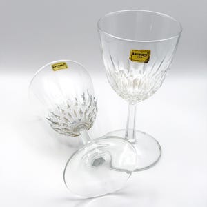 May include: Clear Luminarc USA wine glasses with a diamond-cut pattern on the bowl. One glass is upright, and two are lying down. Each glass has a yellow and black Luminarc USA sticker.