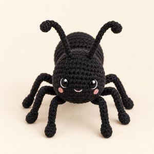 May include: A black crocheted ant toy featuring a rounded head and body, two curved antennae, and six legs. The ant has large black eyes with white highlights and small pink circular patches on its cheeks, with a simple stitched mouth.