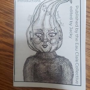 Puede incluir: Un fanzine en blanco y negro titulado "ASHCAN issue 1: New Introductions" con una ilustración detallada de una figura con una cabeza bulbosa. El fanzine está editado por Jacky y publicado por Eau Claire Collective.