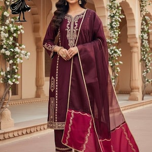 Puede incluir: Un conjunto de salwar kameez burdeos con bordados dorados. El atuendo incluye una t&uacute;nica de manga larga, pantalones a juego y una dupatta transparente. El dise&ntilde;o presenta intrincados patrones dorados en el escote, las mangas y el dobladillo.