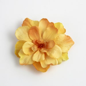 May include: A yellow fabric flower with multiple layers of petals.