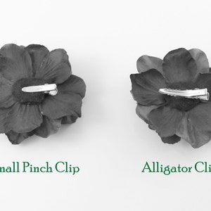 May include: Two black fabric flower hair clips, one with a small pinch clip and the other with an alligator clip.