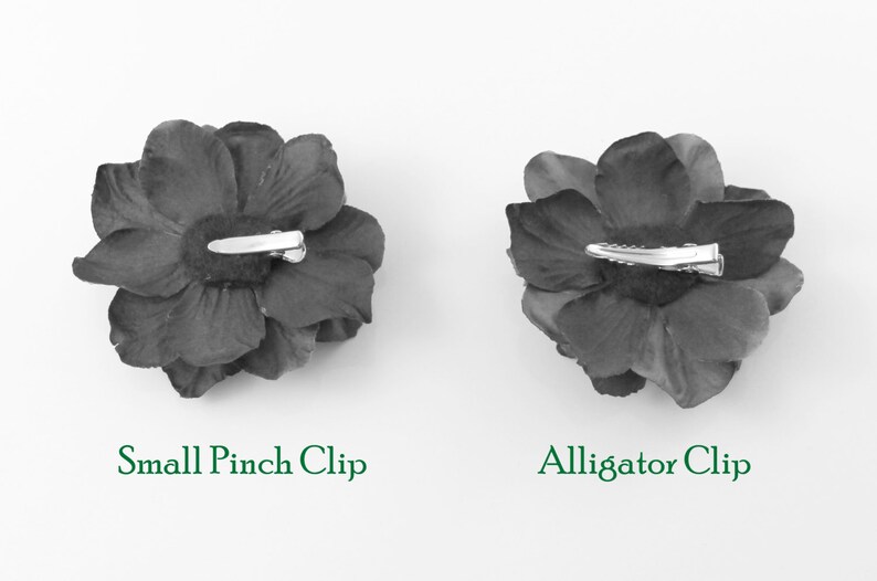 May include: Two black fabric flower hair clips, one with a small pinch clip and the other with an alligator clip.
