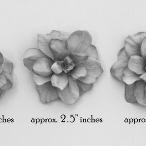 May include: Three gray fabric flower embellishments in different sizes. The smallest flower measures approximately 2 inches in diameter, the middle flower measures approximately 2.5 inches in diameter, and the largest flower measures approximately 3 inches in diameter.