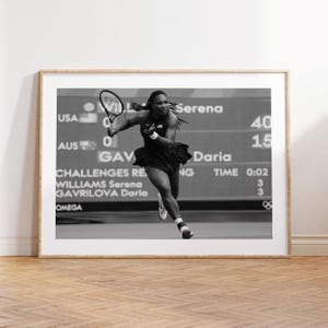May include: Black and white framed print of Serena Williams playing tennis. The image shows Serena in action, holding a tennis racket, with text including "Serena", "GAV", and "Daria". The background displays score details and the Omega logo.