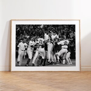 May include: Black and white framed print of a baseball team celebrating a victory. Players in pinstripe uniforms are embracing and jumping in the air. The image is set against a blurred background of spectators.