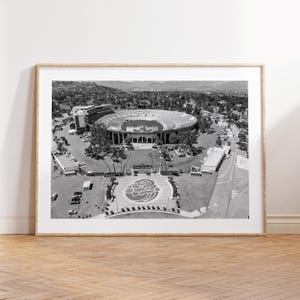 May include: Black and white framed print of the Rose Bowl stadium. The aerial view shows the stadium, surrounding landscaping, and parking areas. The Rose Bowl logo is visible in the foreground.