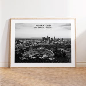 May include: Black and white framed print of Dodger Stadium in Los Angeles, California. The stadium is in the foreground, with the city skyline in the background. Text at the top reads "Dodger Stadium Los Angeles Dodgers."