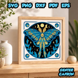 May include: A square framed wall art piece featuring a layered paper-cut design of a moth in shades of blue and gold. The central moth is set against a black circular background with moon phases, stars, and leaf motifs. Text reads SVG PNG DXF PDF EPS.
