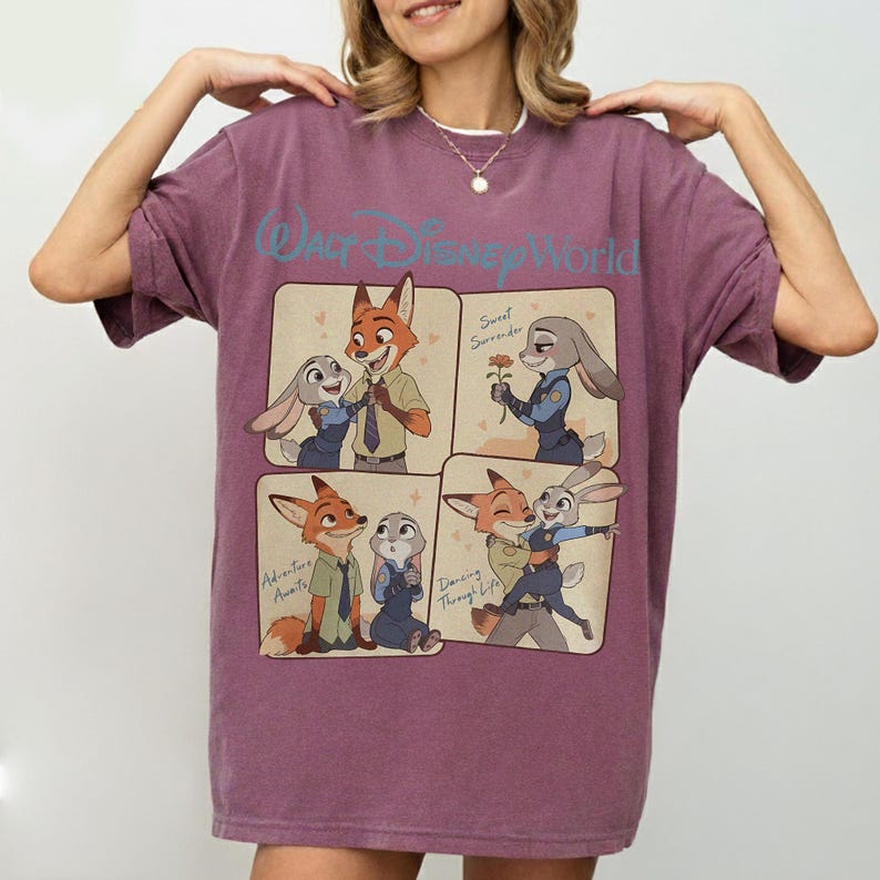 May include: A mauve t-shirt with a graphic of Nick Wilde and Judy Hopps from Zootopia. The shirt has the text "Walt Disney World" above the graphic and the phrases "Sweet Surrender", "Adventure Awaits", and "Dancing Through Life".