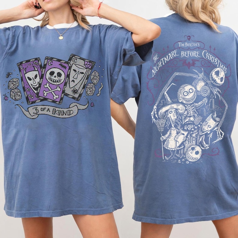 May include: Blue t-shirts featuring graphics from "The Nightmare Before Christmas." The front of the shirt displays three playing cards with character faces and the text "3 of a kind." The back has a larger design with characters and the movie title.