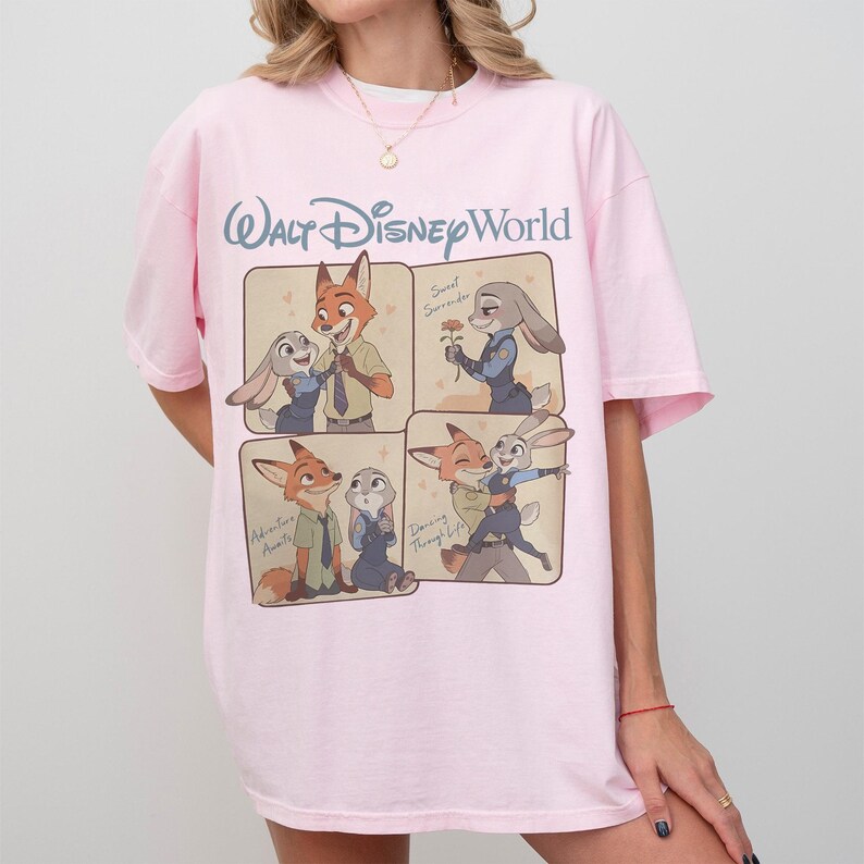 May include: Pale pink t-shirt with a Walt Disney World logo and Zootopia character illustrations. The design includes four panels showing Nick Wilde and Judy Hopps, with text such as "Sweet Surrender" and "Dancing Through Life".