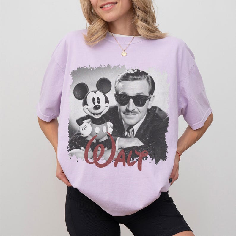 K&ouml;nnte beinhalten: Helllila T-Shirt mit einem Schwarz-Wei&szlig;-Bild von Walt Disney und Mickey Mouse. Das Wort "WALT" ist in roter Schrift gedruckt. Das T-Shirt ist im l&auml;ssigen Stil gehalten.