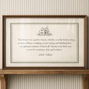 Könnte beinhalten: Gerahmter Druck mit einem Zitat von J.R.R. Tolkien und einer kleinen Hausillustration. Der Text ist in einer Serifenschrift auf cremefarbenem Hintergrund mit dekorativem Rand. Der Rahmen ist braun.