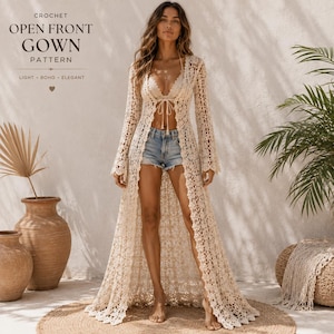May include: A cream-colored, floor-length crochet open-front gown with long sleeves and a delicate lace-like pattern. The garment features a tie closure at the chest and is worn over a light-colored bralette and blue denim shorts.