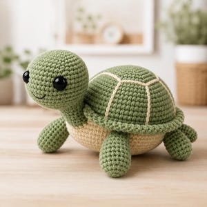 May include: A crochet turtle toy featuring a sage green head, limbs, and shell with cream-colored accents on the shell segments and underbelly. The turtle has large, round, black plastic eyes and a simple stitched smile on its face.
