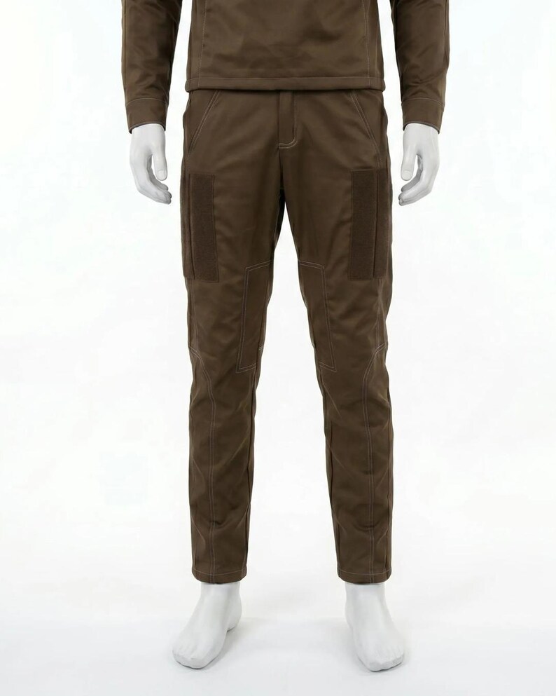 May include: Brown pants with two rectangular pockets on the thighs and white stitching. The pants are part of a matching set, with a long-sleeved top visible above. The pants are displayed on a mannequin.