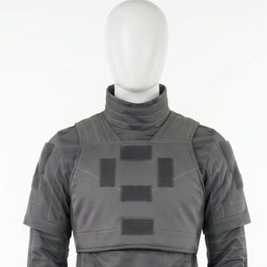 Puede incluir: Un chaleco t&aacute;ctico gris con cuello alto y mangas cortas se muestra en un maniqu&iacute;. El chaleco presenta m&uacute;ltiples parches rectangulares y est&aacute; hecho de un material liso y mate. La cabeza del maniqu&iacute; es blanca.