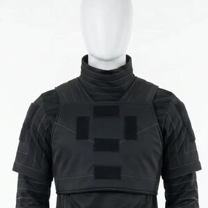 Pode incluir: Colete t&aacute;tico preto com gola alta e ombreiras. O colete apresenta patches retangulares no peito e &eacute; usado sobre uma camisa preta de manga comprida. O manequim est&aacute; sobre um fundo branco.