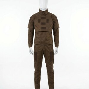 May include: A brown tactical uniform displayed on a mannequin. The outfit includes a long-sleeved shirt with a high collar, a chest plate, and matching pants. The uniform has several square patches and pockets.